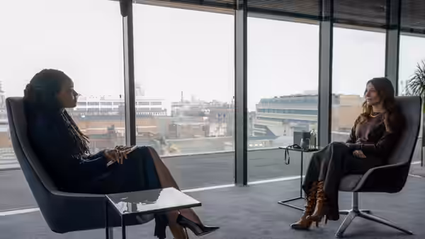 Two women seated in armchairs in a bright modern office
