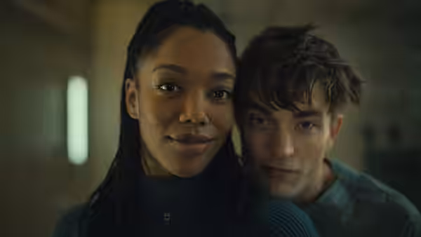 Nasha (Naomi Ackie) and Mickey Barnes (Robert Pattinson) standing close