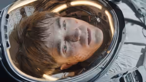 Mickey Barnes (Robert Pattinson) inside a dirty spacesuit helmet
