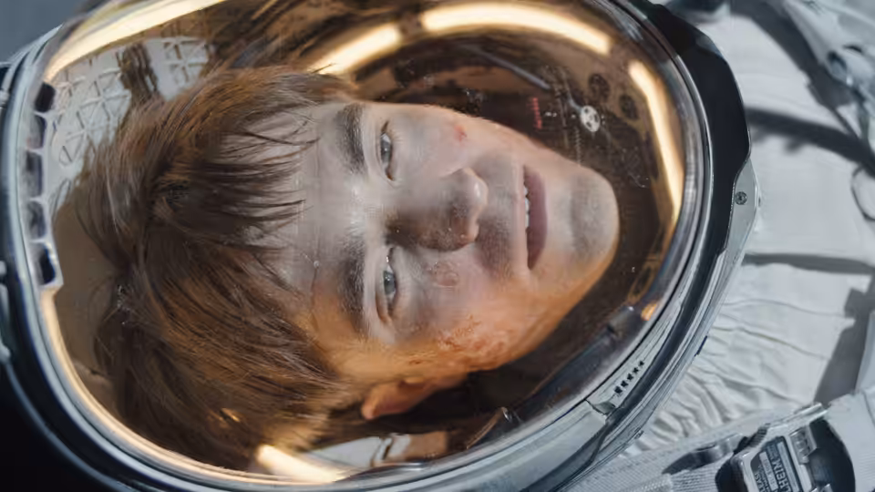 Mickey Barnes (Robert Pattinson) inside a dirty spacesuit helmet