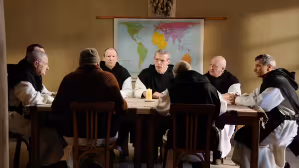 Monks seated around a long table during a meeting