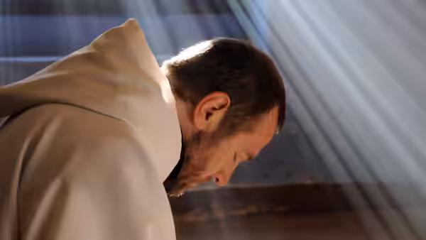 Christian (Lambert Wilson) bowing his head in sunlight