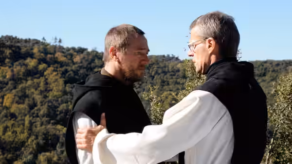 Christian (Lambert Wilson) embraced by Luc (Michael Lonsdale) outdoors