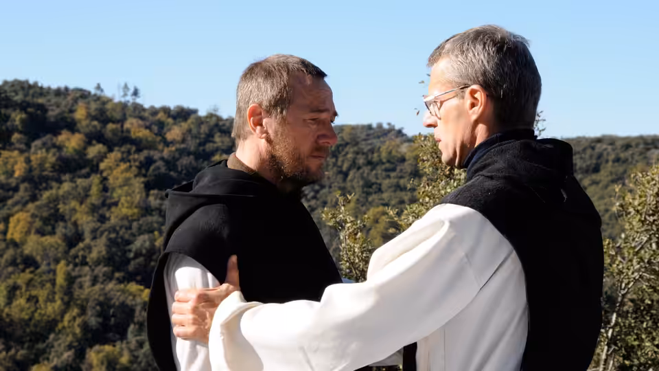 Christian (Lambert Wilson) embraced by Luc (Michael Lonsdale) outdoors