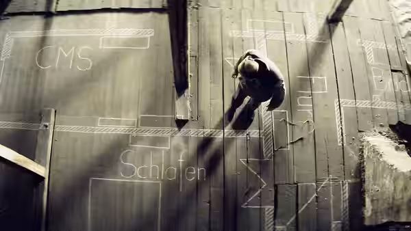 a man lying on a wooden floor marked with chalk diagrams and words