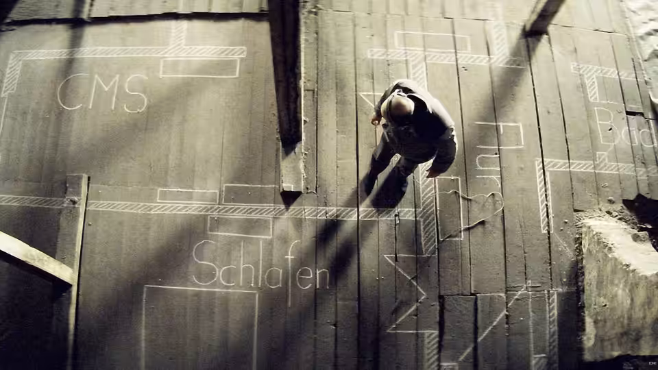 a man lying on a wooden floor marked with chalk diagrams and words