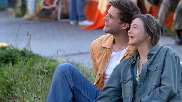 Roxby McDuff (Leo Woodall) and Bridget Jones (Renée Zellweger) sitting on grass laughing