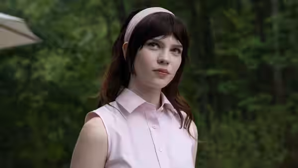Iris (Sophie Thatcher) wearing a pink headband and shirt in a forest