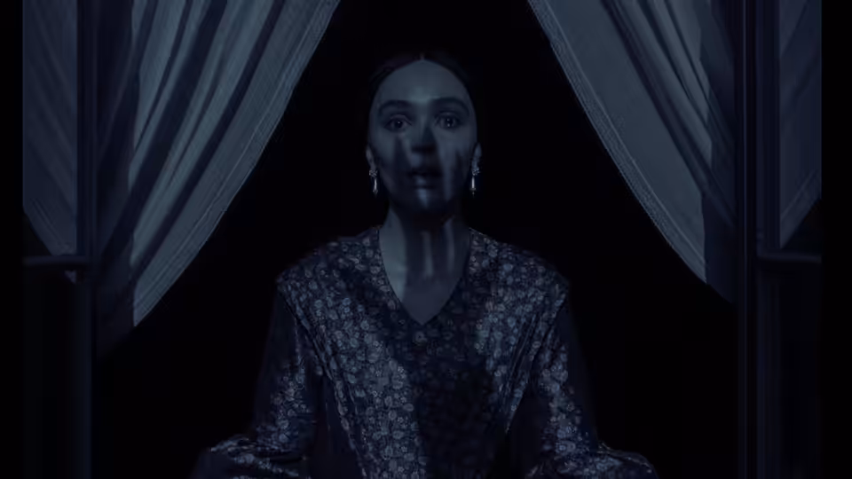 Ellen Hutter (Lily-Rose Depp) standing wide-eyed between dark curtains