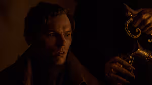 Thomas Hutter (Nicholas Hoult) holding an ornate candlestick in shadow