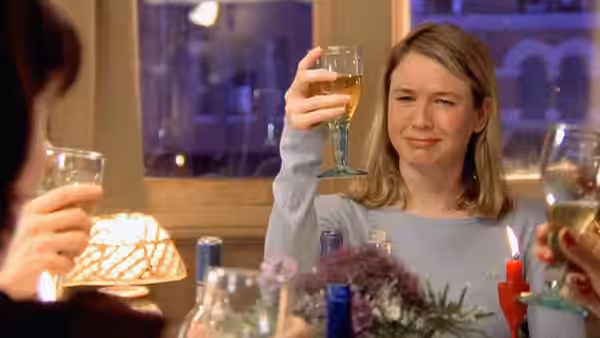 Bridget Jones (Renée Zellweger) raising a glass at a dinner table with friends