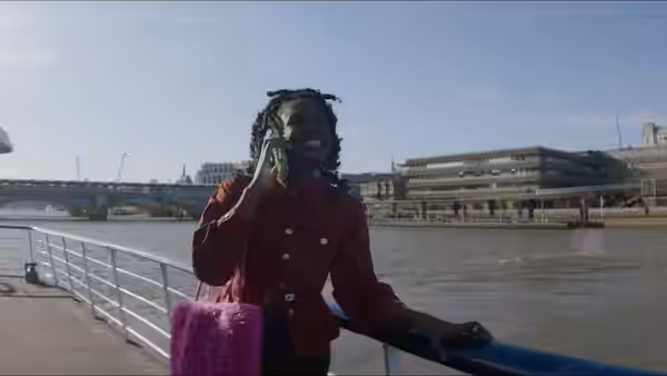 Yas (Vivian Oparah) talking on her phone by the river