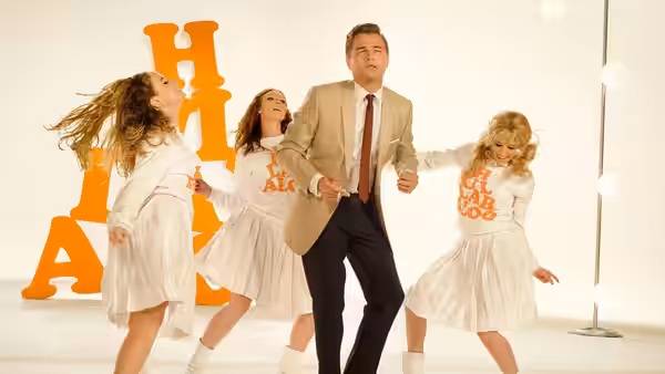 Rick Dalton (Leonardo DiCaprio) dancing with three women in white outfits on a set