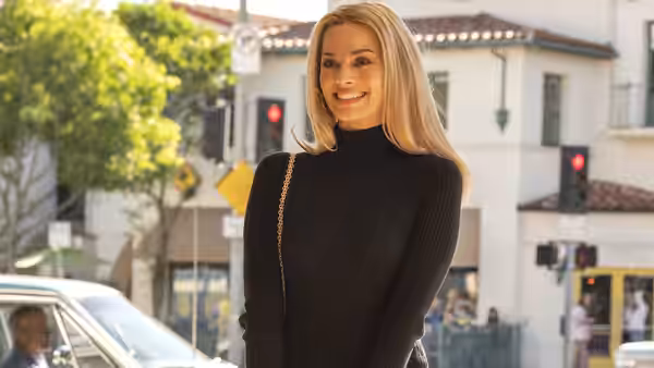 Sharon Tate (Margot Robbie) smiling on a sunny city sidewalk