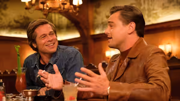 Rick Dalton (Leonardo DiCaprio) and Cliff Booth (Brad Pitt) conversing at a restaurant table