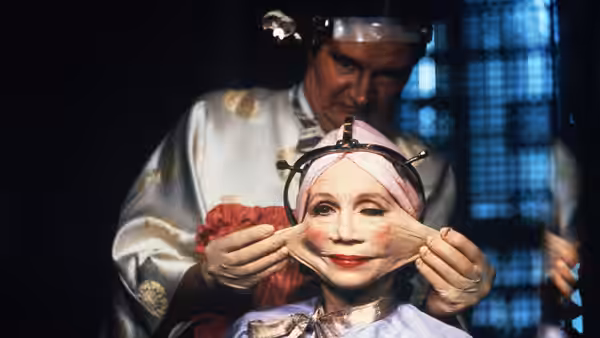 Mrs. Ida Lowry (Katherine Helmond) having facial skin stretched by gloved hands