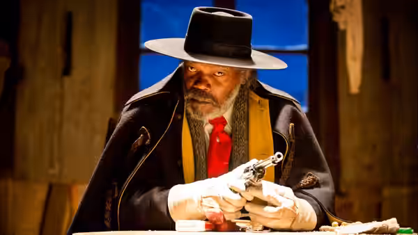 Major Marquis Warren (Samuel L. Jackson) inspects a revolver at a wooden table
