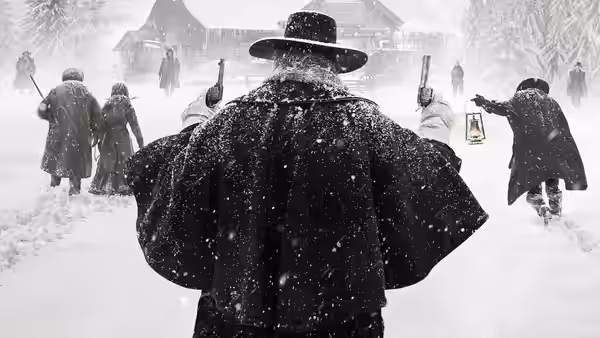 Armed figures in heavy coats walk through falling snow toward wooden buildings