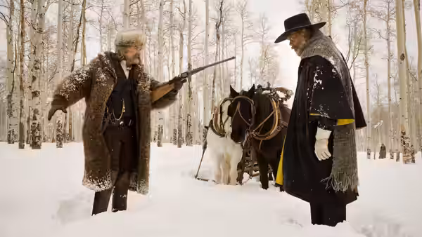 John Ruth (Kurt Russell) faces Major Marquis Warren (Samuel L. Jackson) beside horses in snow