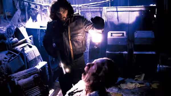 MacReady (Kurt Russell) shining a flashlight on a body in a cluttered room