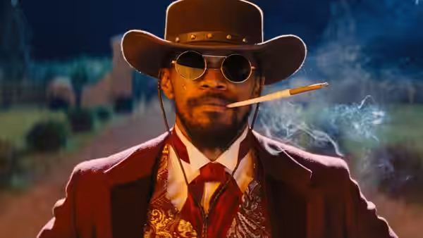 Django (Jamie Foxx) in a red suit and hat smoking a cigarette at night