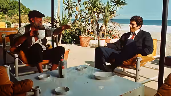 Roger Wade (Sterling Hayden) gestures while talking with Philip Marlowe on a sunny patio