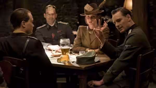Colonel Hans Landa gesturing at a table with officers and a woman
