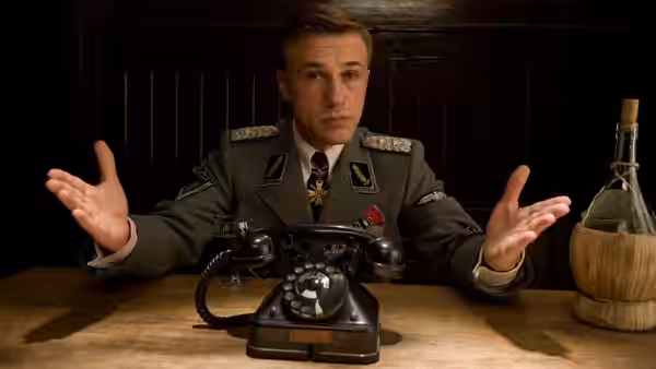 A German officer at a desk with a telephone, hands raised