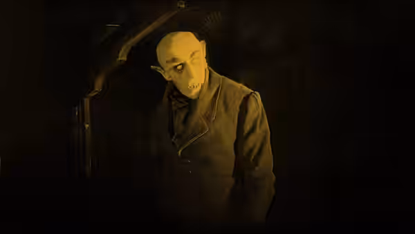 Count Orlok (Max Schreck) hunches beneath a doorway in a dark room