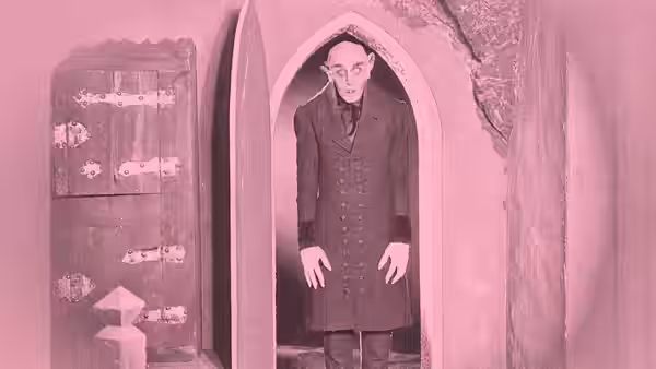 Count Orlok (Max Schreck) stands in a doorway beside an open chest