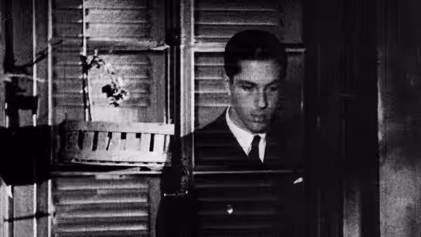 Allan Grey (Nicolas de Gunzburg) appears behind the slatted shutters of a window