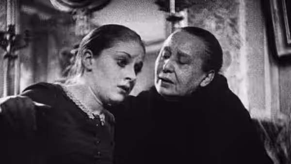 A young woman leans close to an older woman indoors
