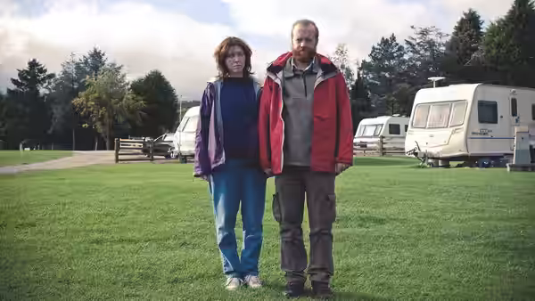 Tina (Alice Lowe) and Chris (Steve Oram) standing together in a grassy field