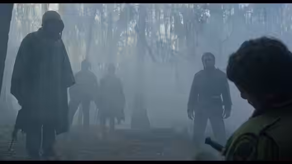 Soldiers stand among trees in thick fog with one kneeling