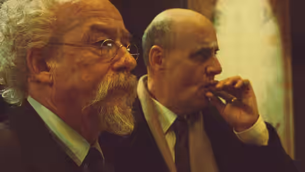 Professor Bruttenholm (John Hurt) next to Tom Manning (Jeffrey Tambor) smoking a cigar