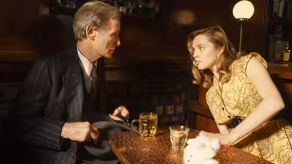 Williams (Bill Nighy) speaks with Margaret Harris (Aimee Lou Wood) across a pub table