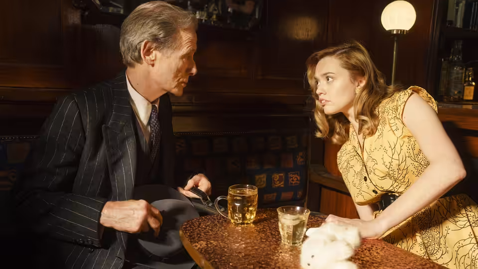 Williams (Bill Nighy) speaks with Margaret Harris (Aimee Lou Wood) across a pub table