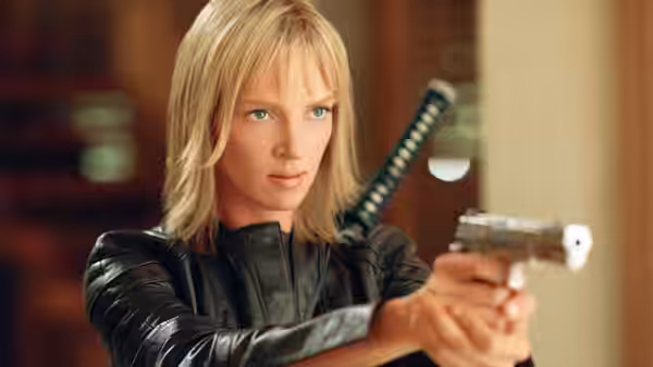 Beatrix Kiddo (Uma Thurman) aiming a pistol with katana on her back