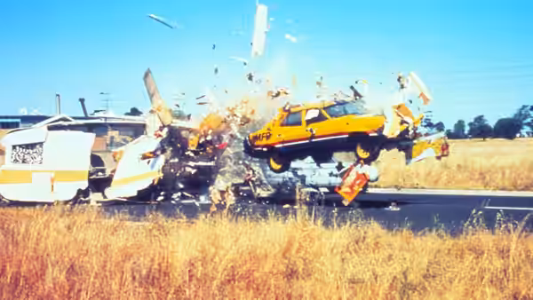 Yellow car exploding mid-air during a crash with flying debris