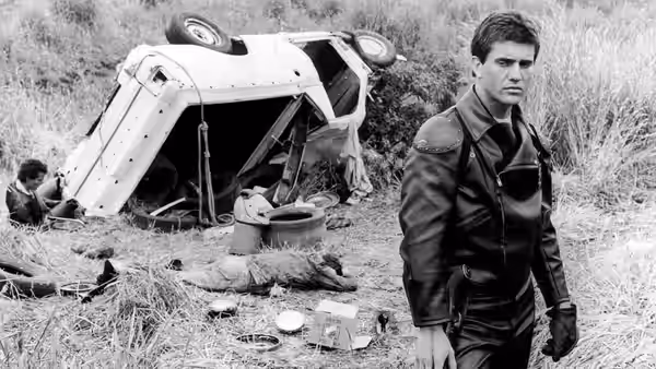 Max Rockatansky (Mel Gibson) standing near an overturned car in a field