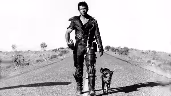 Max Rockatansky (Mel Gibson) walking a dog on a remote paved road