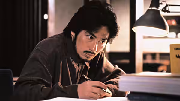 Ryuji Takayama (Hiroyuki Sanada) writing at a desk under a lamp