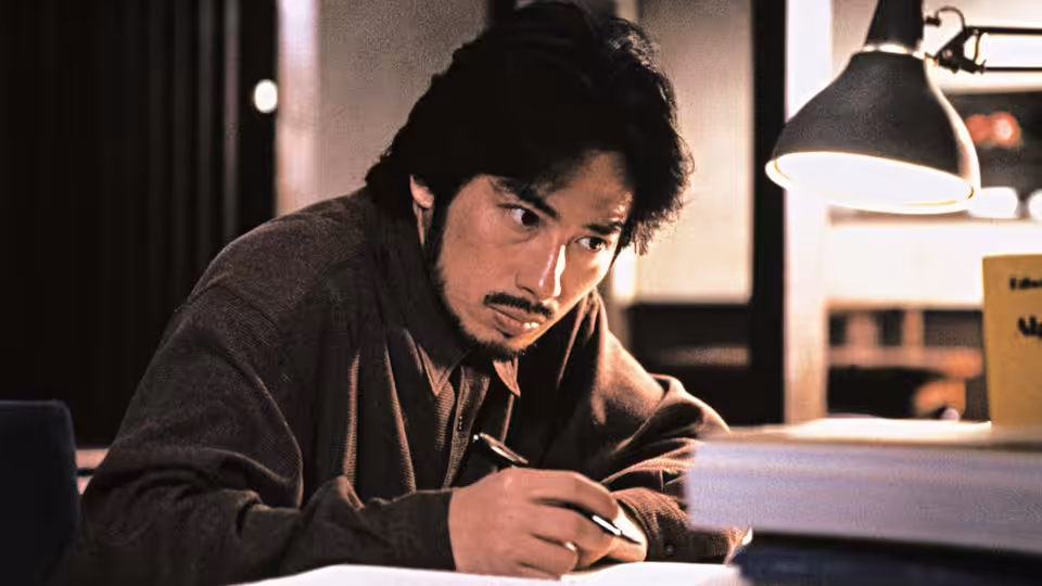 Ryuji Takayama (Hiroyuki Sanada) writing at a desk under a lamp