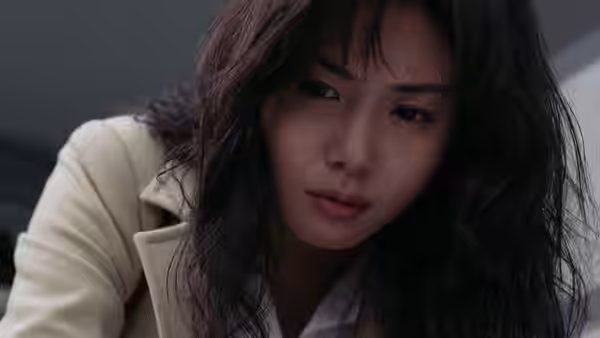Reiko (Nanako Matsushima) leans forward in a pale coat, looking down