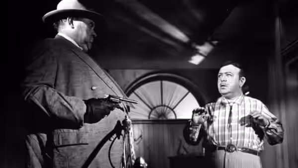 Captain Quinlan (Orson Welles) points a gun at the motel night manager (Dennis Weaver) indoors