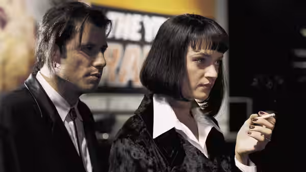 Vincent Vega (John Travolta) beside Mia Wallace (Uma Thurman) holding a cigarette