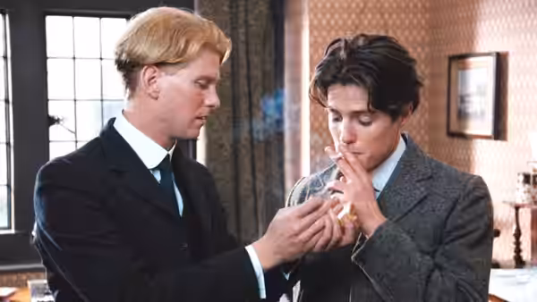 Clive Durham (Hugh Grant) lights a cigarette for Maurice Hall (James Wilby) indoors