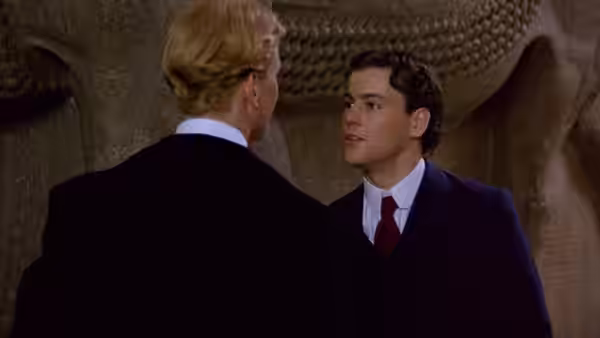 Maurice Hall (James Wilby) speaks with Clive Durham (Hugh Grant) beneath a stone sculpture
