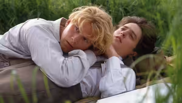 Clive Durham (Hugh Grant) embraces Maurice Hall (James Wilby) as they lie in the grass