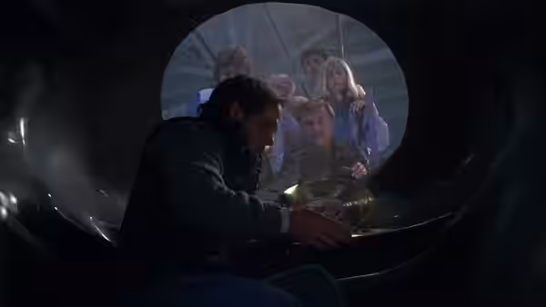 Starman (Jeff Bridges) crouches inside a capsule as officials peer through its opening